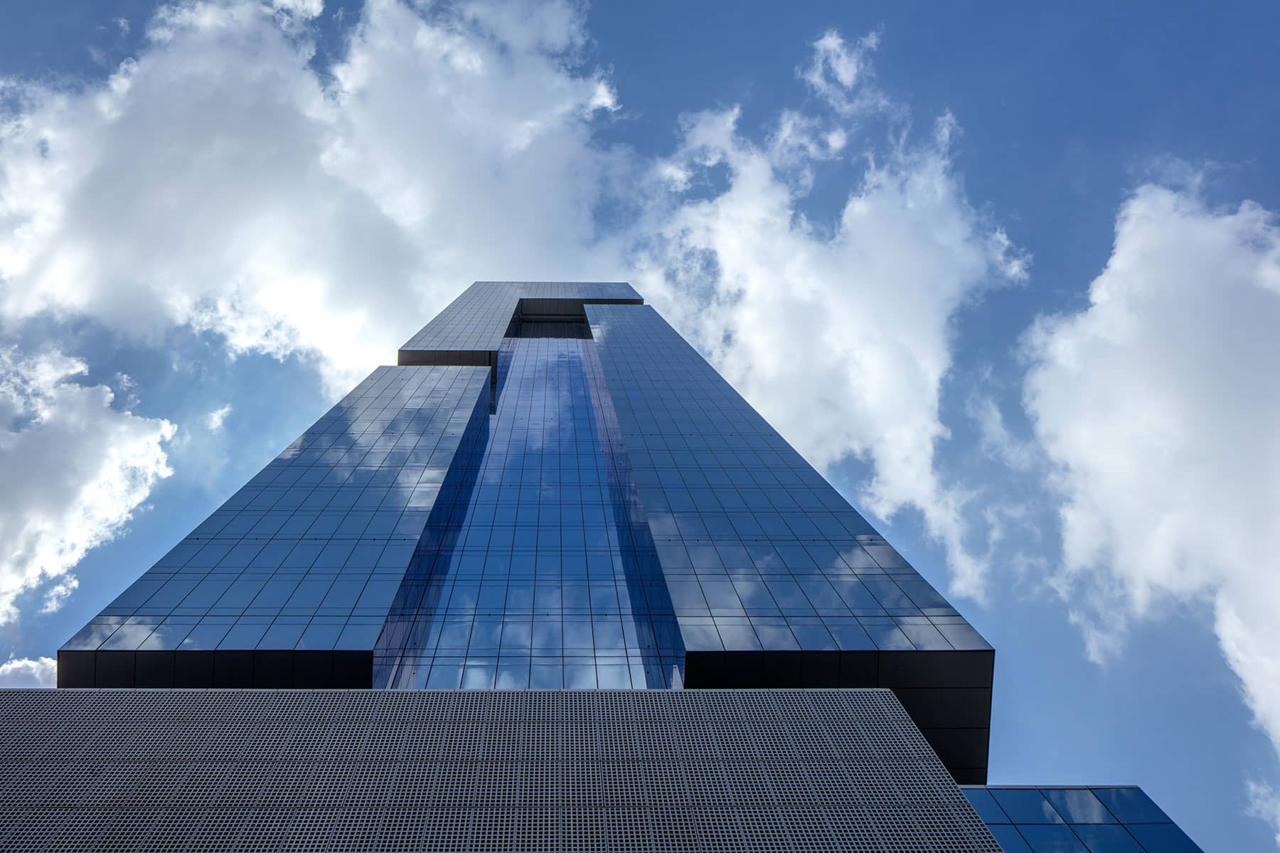 Architecture Photography: A skyward perspective of the glass façade reflecting the clouds at the First Collection.
